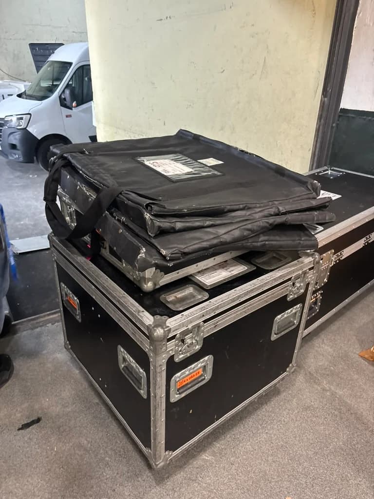 Stacked flight cases and padded equipment bags beside a loading-bay doorway