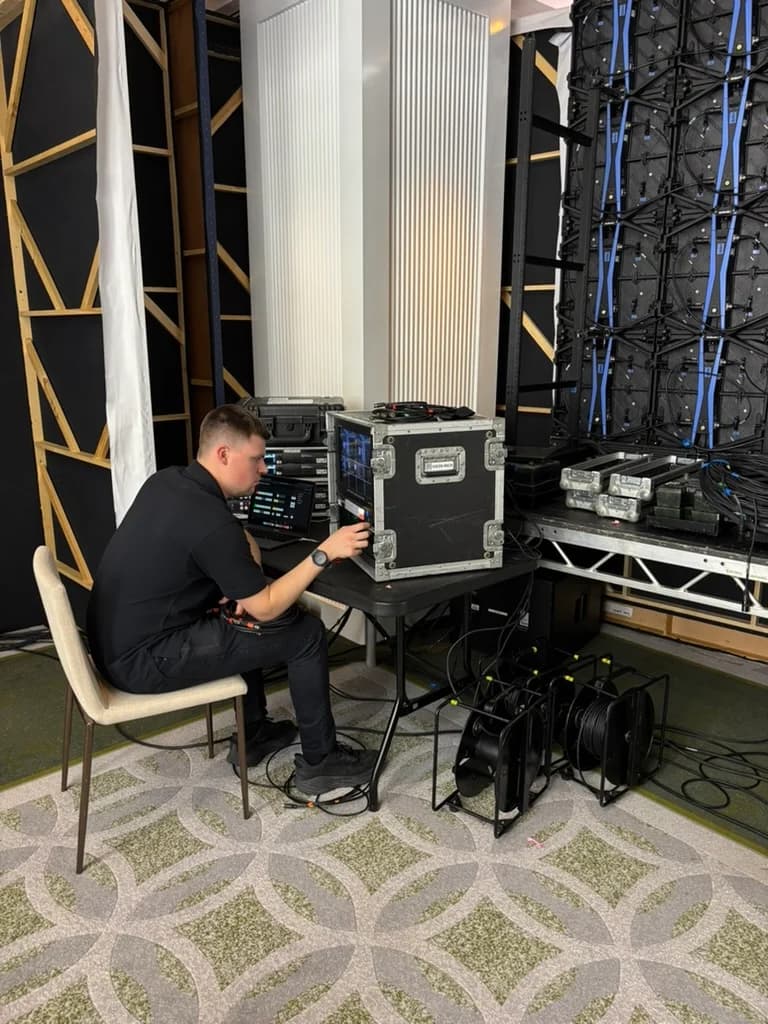 A technician operating equipment beside the rear of a display wall