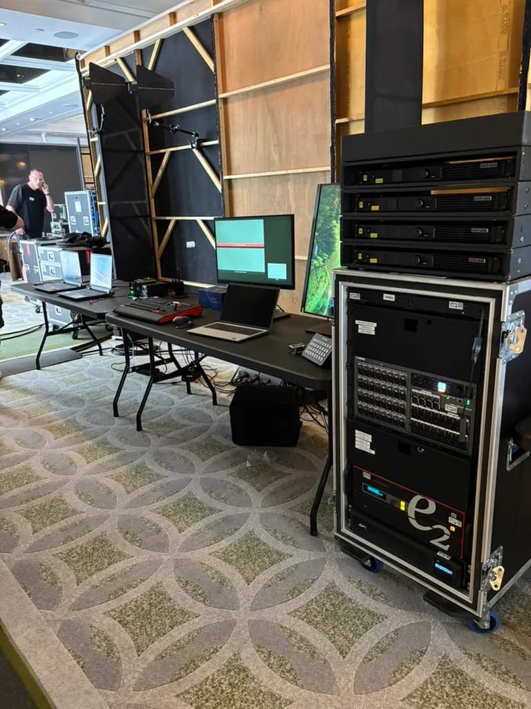 Laptops, monitors and video equipment racks behind the stage set