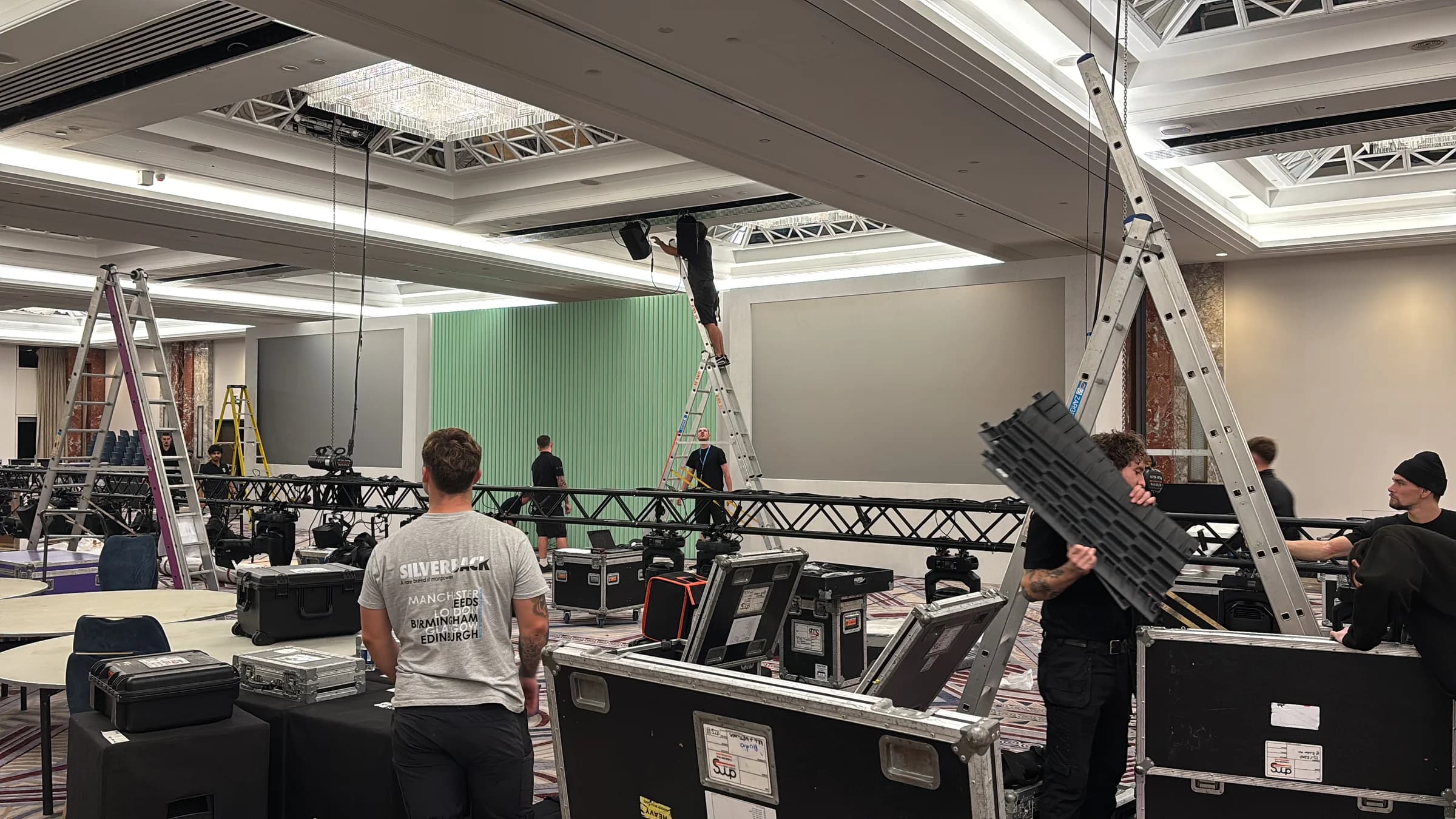 Crew working around flight cases and a lighting truss in front of the stage backdrop