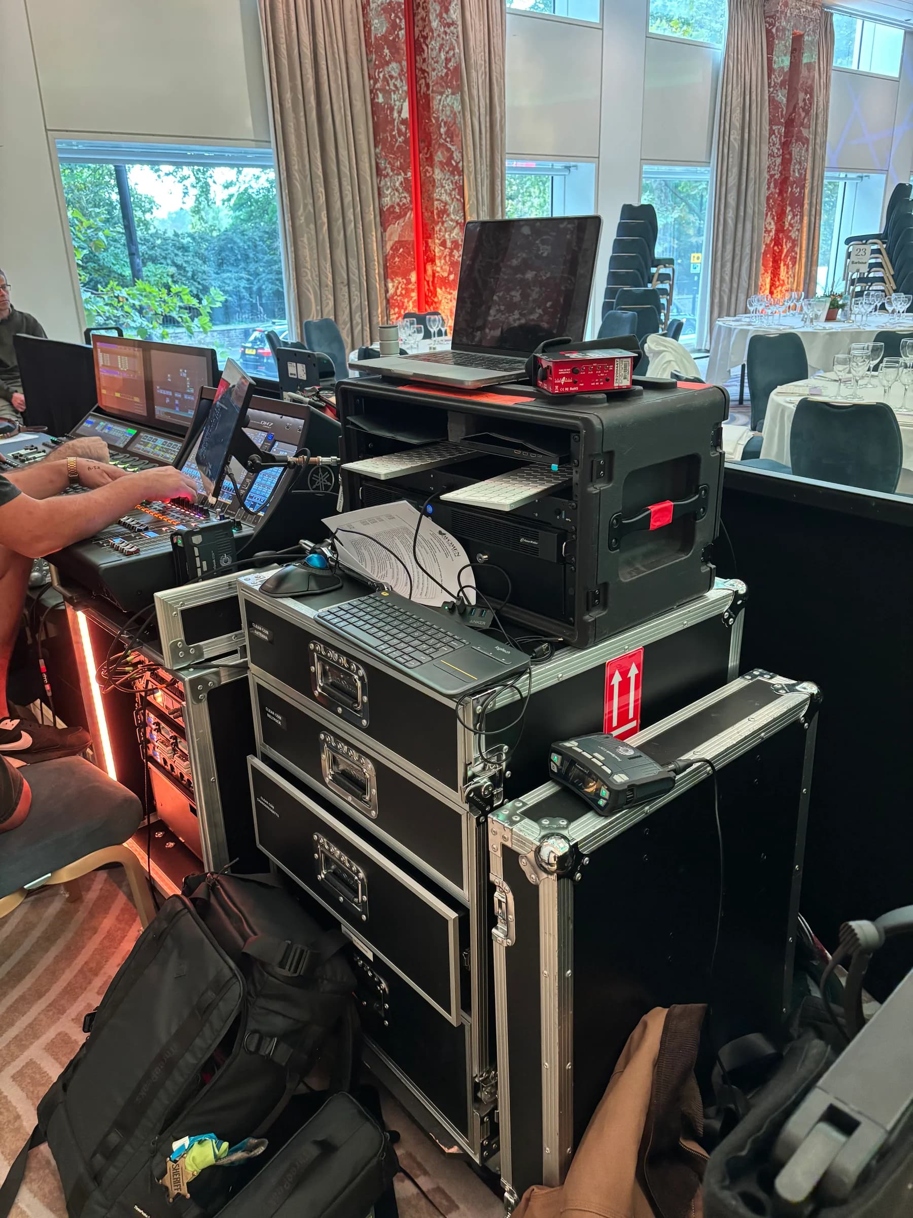 Audio mixing console, laptops and equipment racks beside the ballroom seating