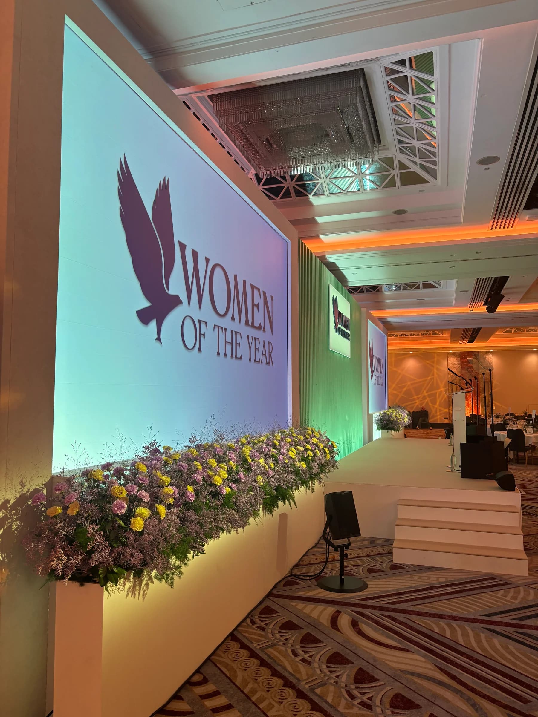 Side view of the Women of the Year stage with screens, floral arrangements and white steps